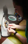 Bir masa başında bir büyüteçle oturan kadın